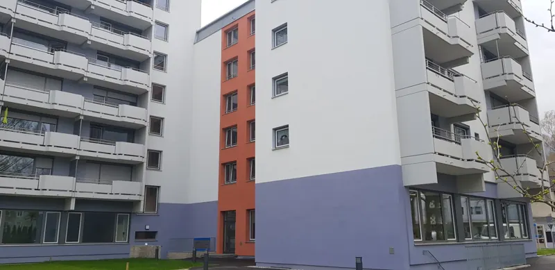 Wohnanlage mit neu gestrichener Fassade in Weiß, Lavendel und Terrakotta